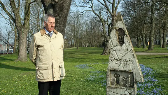 Zeitzeuge Hans-Otto Mutschler steht in Lübeck neben einer Stele, die an den Todesmarsch von KZ-Häftlingen 1945 erinnert.