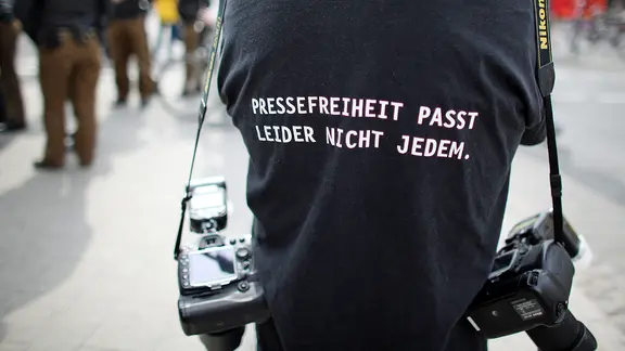 Ein Fotograf trägt ein T-Shirt mit einem Slogan für die Pressefreiheit