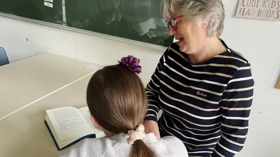 Ein Mädchen und eine Lesepatin lesen gemeinsam ein Buch.