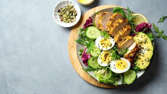 Teller mit Hähnchenbrust, Ei, Avocado und Salat