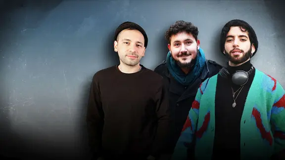 Drei queere Menschen stehen nebeneinander vor einem grau, blauen Hintergrund.