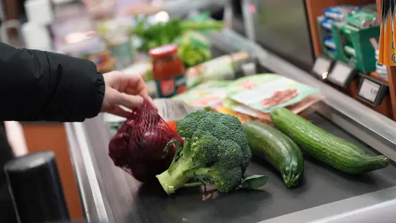 Ein Mann legt seinen Einkauf auf das Laufband an einer Kasse in einem Supermarkt