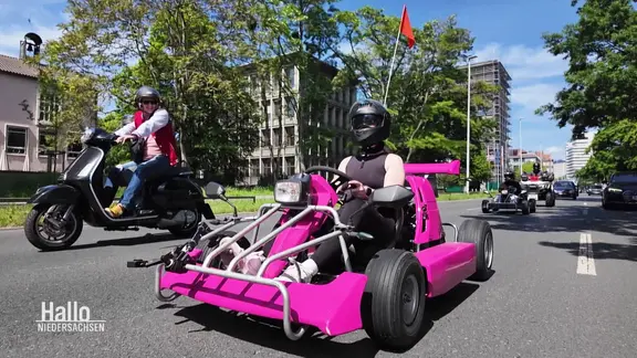 Ein pinkes Kart im Straßenverkehr.