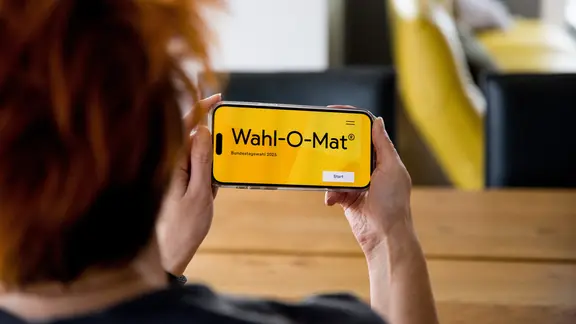 Eine Person benutzt auf dem Handy den Wahl-O-Mat für die Bundestagswahl 2025.
