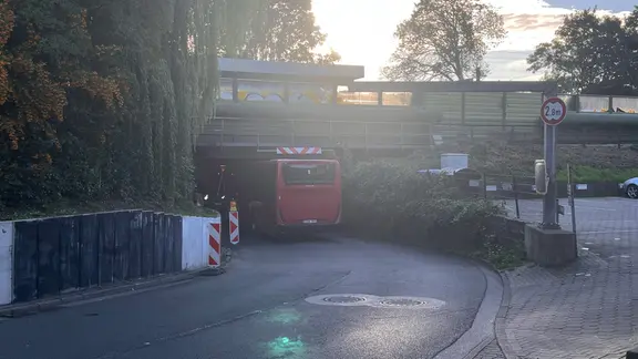Ein stecken gebliebener Bus unter einer Brücke.
