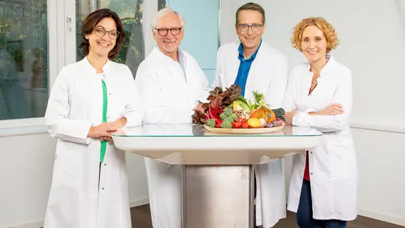 Die vier Ernährungs-Docs Silja Schäfer, Jörn Klasen, Matthias Riedl und Viola Andresen stehen auf dem Hausboot am Tisch.