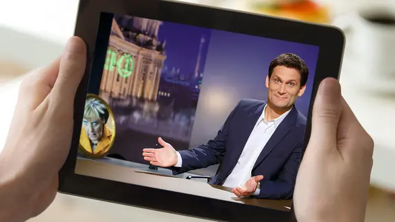 Auf einem Tablet spielt ein Video von Extra mit Christian Ehring.