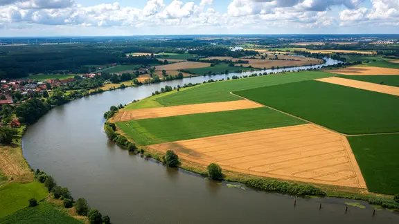 Der Fluss Weser fließt entlang von Feldern.