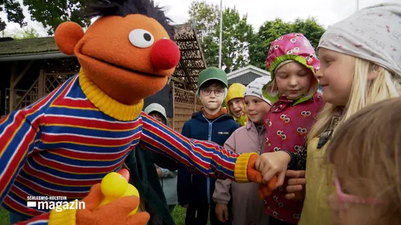 Die Sesamstraßenfigur Ernie im Gespräch mit einigen Kindern