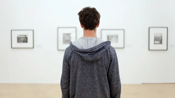 Ein Mann steht vor Bildern in einem Museum.