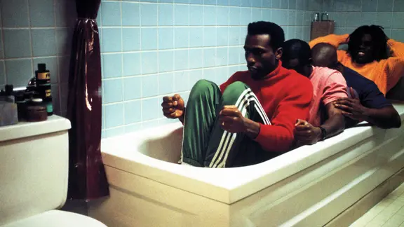 Vier Männer sitzen in einer Badewanne und simulieren Bobfahren, Szene aus "Cool Runnings"