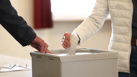 Eine Frau wirft ihren Stimmzettel in eine Wahlurne.