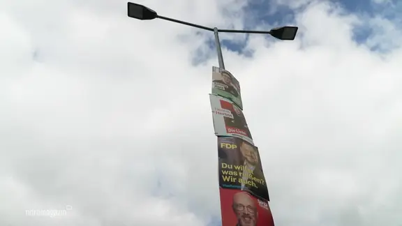 Wahlplakate hängen übereinander an einer Laterne.