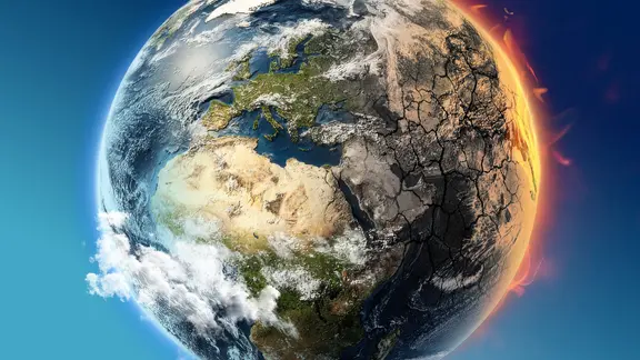 Halb grüne Erde, halb verbrannte, rissige Fläche - Symbolbild für Klimawandel.