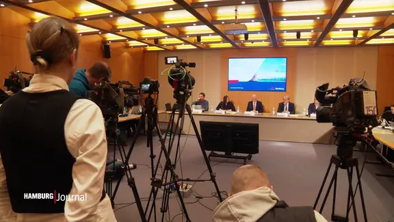 Blick in einen kleinen Saal, in dem eine Pressekonferenz des Hamburger Senats stattfindet.