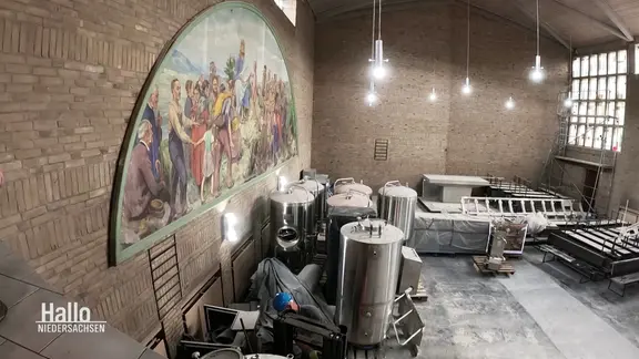 Brauerei-Technik vor einem religiösen Wandbild in einer alten Kirche.