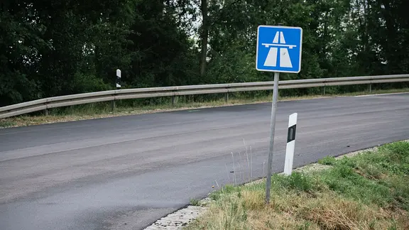 Ein Verkehrszeichen am rechten Fahrbahnrand weist auf den Beginn einer Autobahn hin.