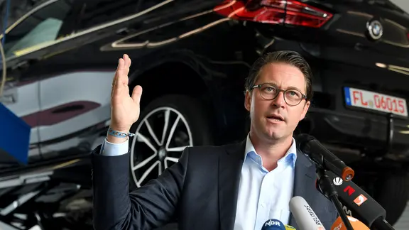 Bundesverkehrsminister Andreas Scheuer (CSU) steht in einer Werkstatt vor einem Testfahrzeug.