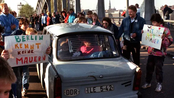 Öffnung der Grenze zwischen Bundesrepublik und DDR. Menschen mit einem Trabi.
