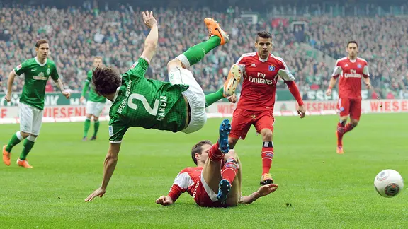 Werders Santiago Garcia fliegt durch die Luft, gefoult von HSV-Profi Dennis Diekmeier (unten)