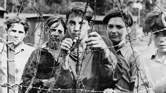Geflüchtete jüdische Kinder von der "Exodus" hinter Stacheldraht in einem Lübecker Lager 1947.