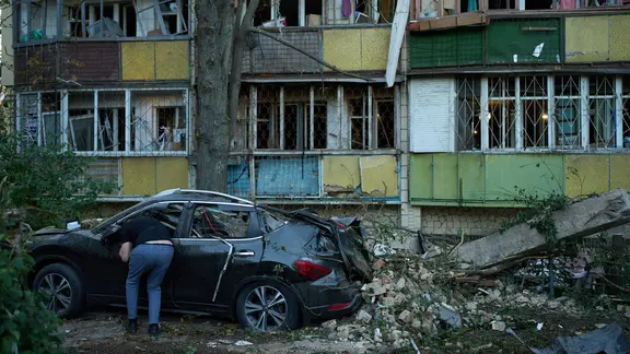 Ukraine, Kiew: Anwohner blickt nach russischen Angriff in zerstörtes Auto.