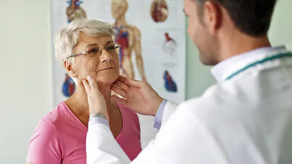 Ein Arzt tastet die Lymphknoten am Hals einer Frau ab.