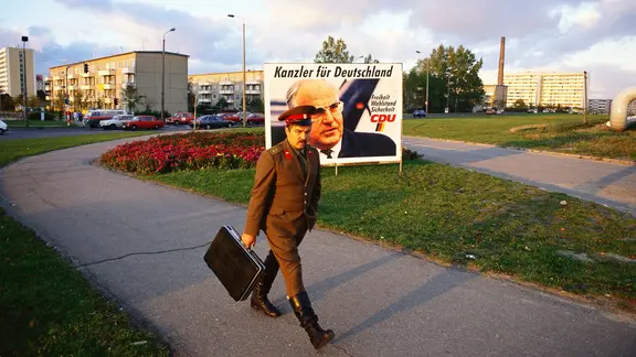 In einem Schweriner Plattenbaugebiet hängt ein Wahlplakat von Helmut Kohl. Davor geht ein Soldat die Straße entlang. (Fotograf: Kurt W. Hamann)