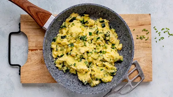 Eine Pfanne mit einem Rührei mit Zucchini.