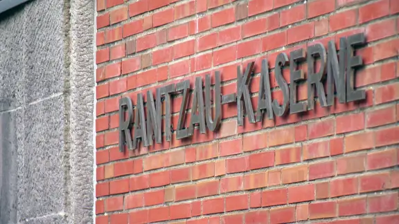 Schriftzug an einer Gebäudewand, schräg von der Seite gefilmt: Rantzau-Kaserne.