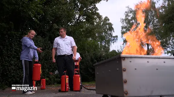 Ein Kind probiert bei einer Übung einen Feuerlöscher aus