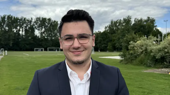 Ein junger Mann mit Brille lächelt in die Kamera