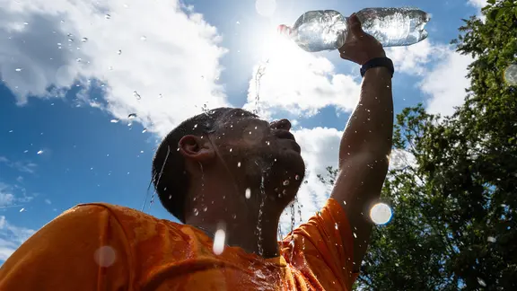 Mann kühlt sich bei sommerlicher Hitze mit Wasser ab