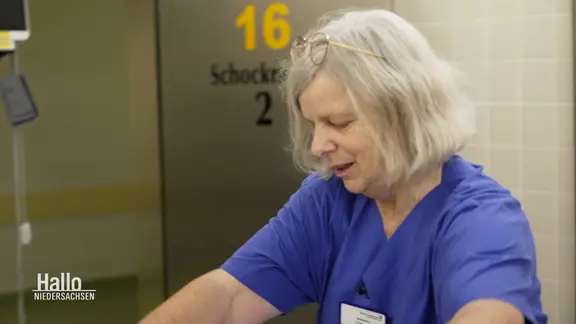 Eine alte Person trägt einen Kasak und befindet sich in einem Krankenhaus.