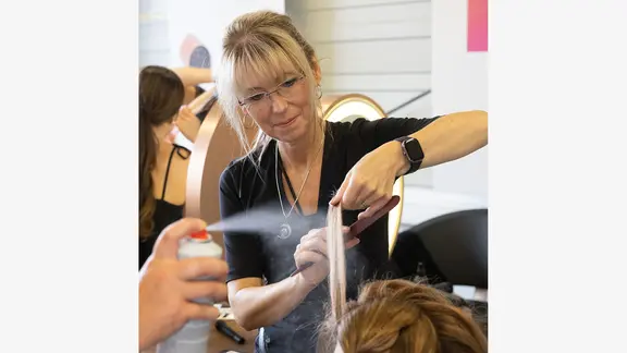 Eine Frau frisiert Haare. Es ist die Friseurmeisterin Daniela Repmann.