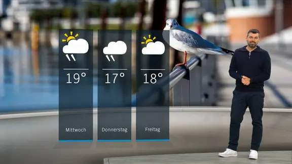 NDR Moderator Sebastian Wache steht im Studio mit der Wettervorhersage.