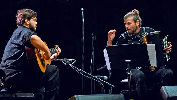 Die Musiker Yamandu Costa und Vincent Peirani bei einem Auftritt auf der Bühne.