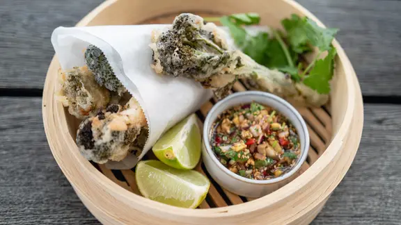 Frittiertes Hähnchen mit Brokkoli und Soja-Sesam-Dip in einem Bambuskorb serviert