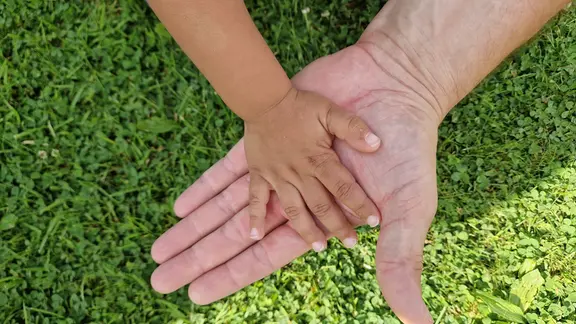 Eine Kinderhand liegt auf einer Erwachsenenhand. 