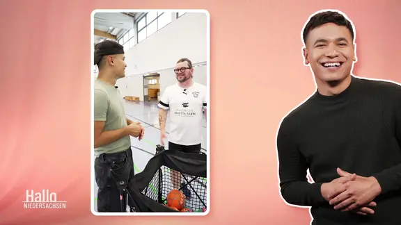 Ein Reporter interviewt einen Handballtrainer auf einem Handybildschirm.