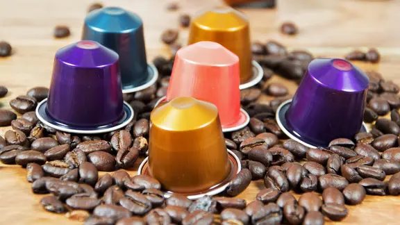 Bunte Kaffeekapseln auf einem Tisch mit Kaffeebohnen