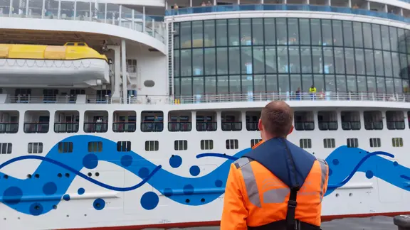 Ein Mann steht vor einem Kreuzfahrtschiff im Hamburger Hafen
