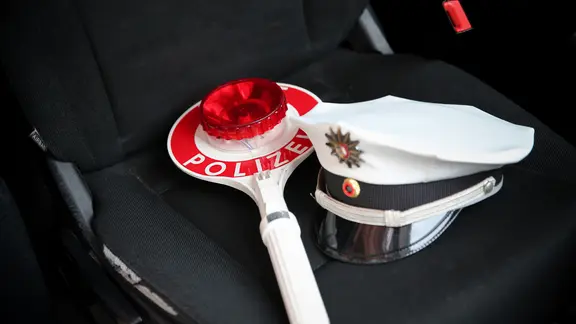 Eine Schirmmütze und eine Polizeikelle liegen auf dem Beifahrersitz eines Streifenwagens.
