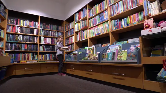 Eine Schülerin steht in der Bibliothek der Otfried-Preußler-Schule in Hannover.