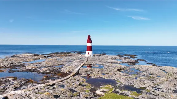 Der rot-weiß gestreifte Leuchtturm Haugjegla steht auf Felsen am Meer