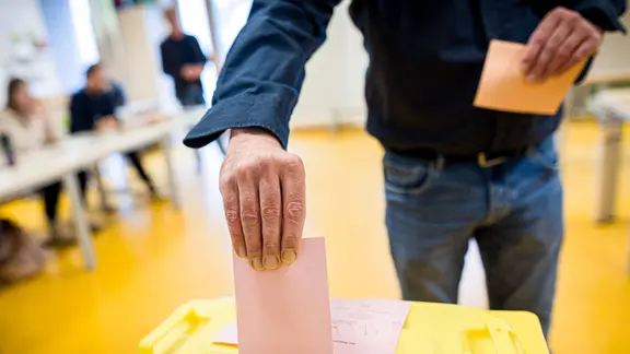 Ein Wähler wirft in einem Wahllokal seinen Stimmzettel in eine Wahlurne.
