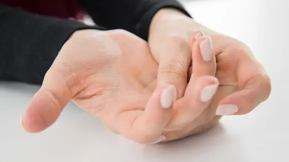 Eine Frau hat Schmerzen in der Hand.