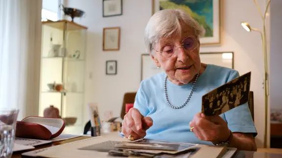 Seniorin Helga Rode schaut sich ein Schwarzweiß-Foto an.