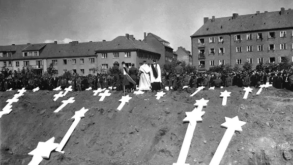 Die Markierungen beziehen sich auf in Ludwigslust gefundene Gräber von 80 Opfern der Nazis. Die gesamte Bevölkerung von Schwerin wurde von der Militärregierung angewiesen, an Beerdigungsritualen teilzunehmen, die von Seelsorgern der US-Armee durchgeführt wurden. (08.05.1945)