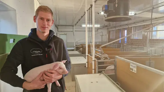 Junglandwirt Eike Alswede hält ein Ferkel